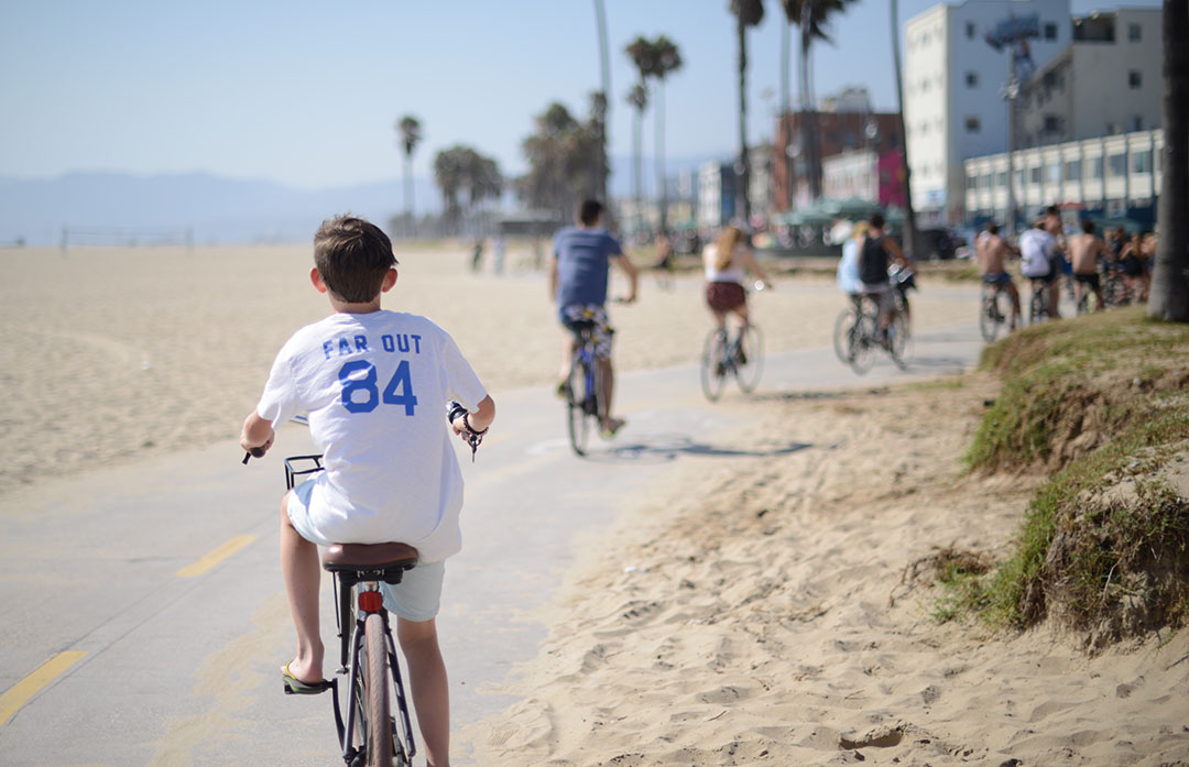 boy cycling on the beach in LA photographed by sara delaney