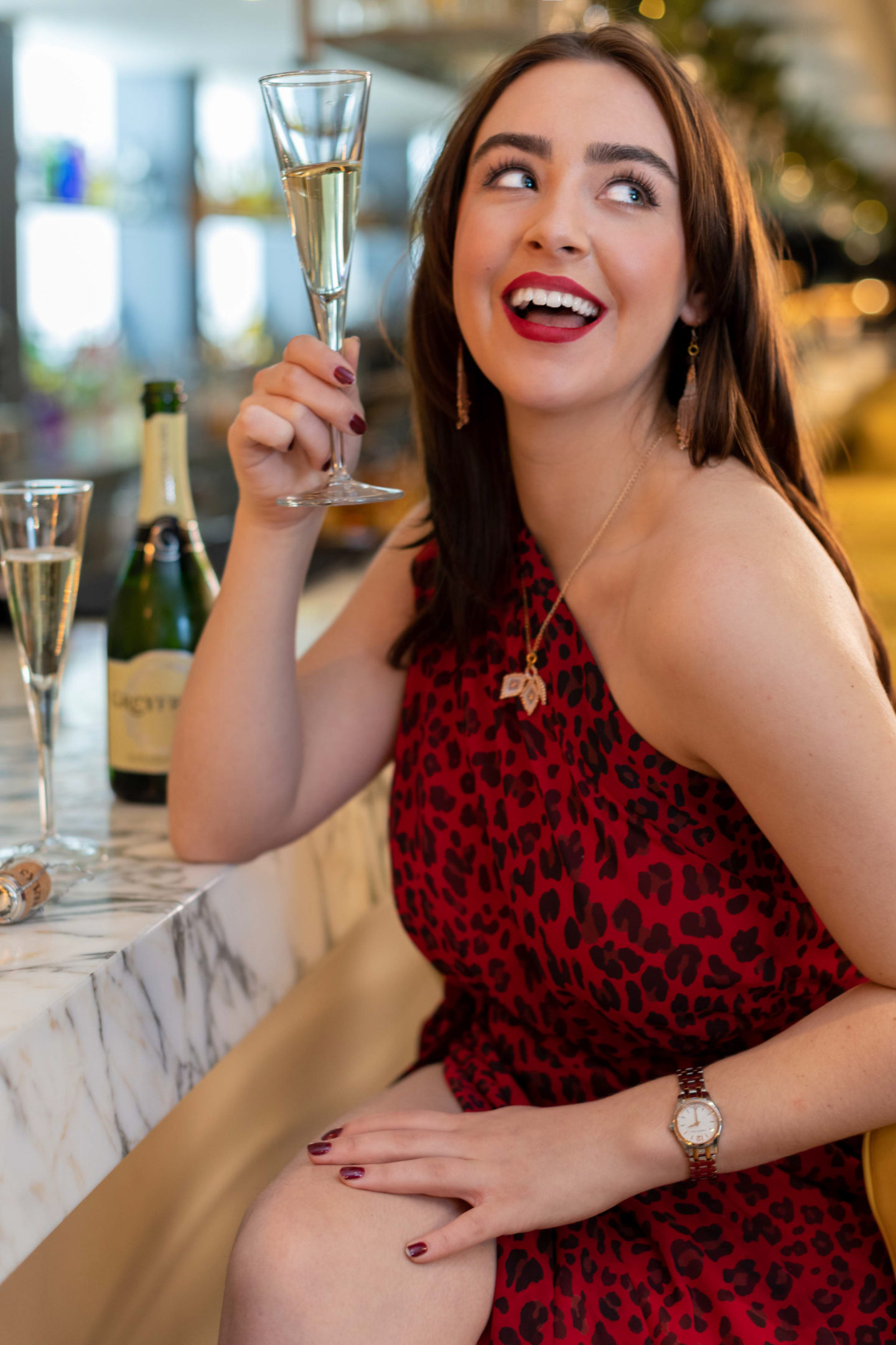 young woman sipping champagne at a bar for a personal branding photography shoot in guiildford